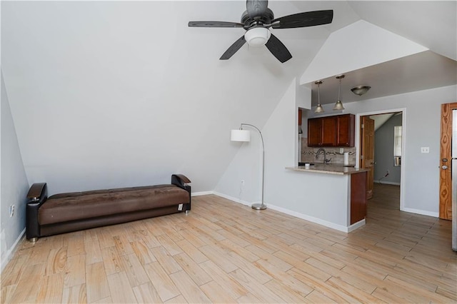 living room featuring vaulted ceiling, ceiling fan, baseboards, and light wood-style floors