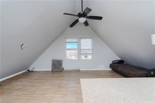 additional living space featuring lofted ceiling, ceiling fan, light wood-style flooring, baseboards, and radiator heating unit