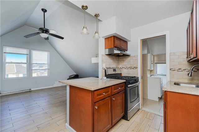 kitchen featuring light stone counters, decorative light fixtures, stainless steel range with gas stovetop, a sink, and under cabinet range hood