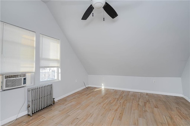 bonus room with light wood-type flooring, baseboards, vaulted ceiling, and radiator heating unit