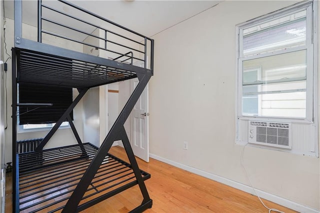 bedroom featuring cooling unit, baseboards, and wood finished floors