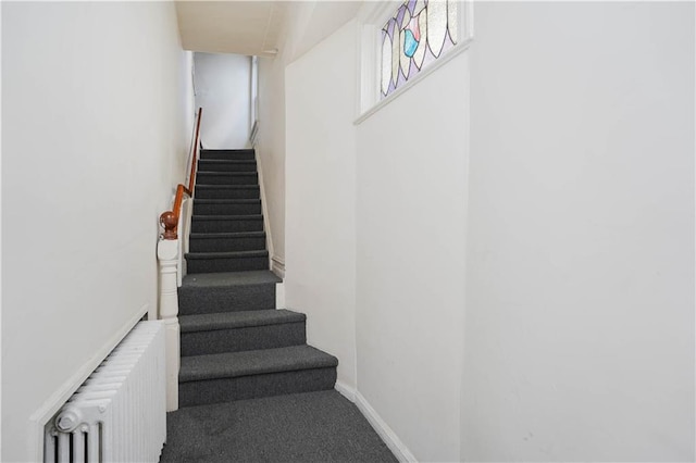 staircase featuring carpet flooring, baseboards, and radiator heating unit