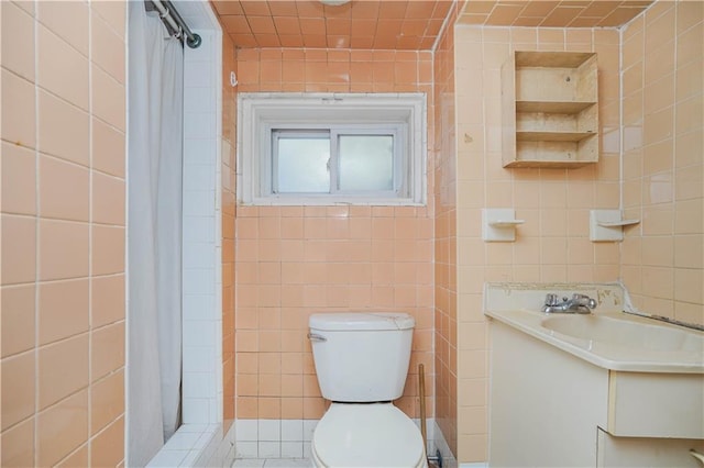 full bath with toilet, a stall shower, vanity, and tile walls