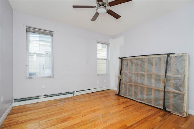 spare room featuring ceiling fan, a baseboard radiator, wood finished floors, and baseboards