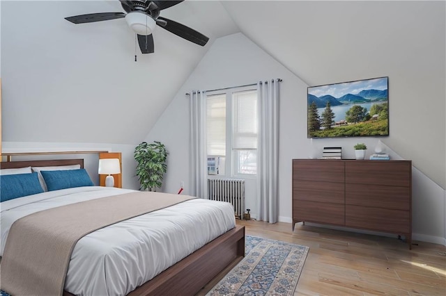 bedroom with radiator, light wood-style flooring, vaulted ceiling, and a ceiling fan