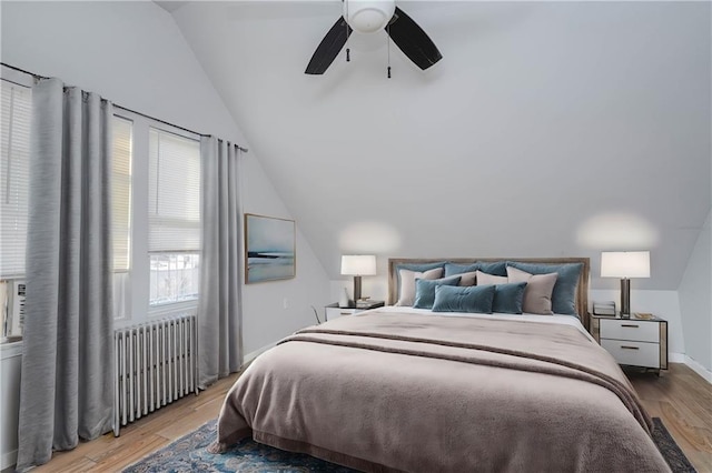 bedroom with baseboards, a ceiling fan, lofted ceiling, radiator heating unit, and light wood-style floors