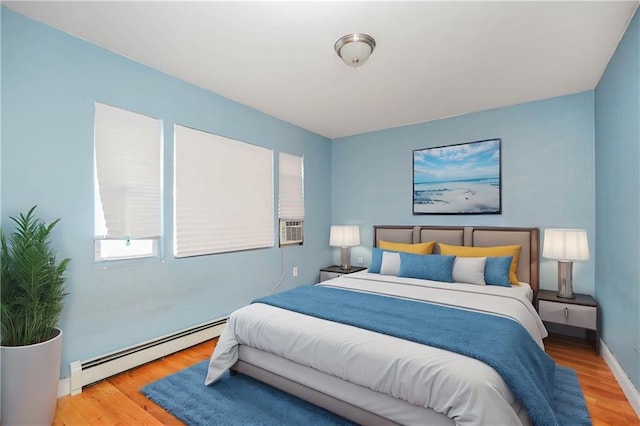 bedroom featuring baseboards, baseboard heating, and wood finished floors