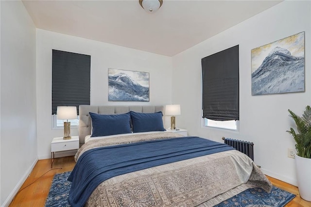 bedroom with radiator heating unit, wood finished floors, and baseboards