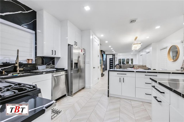 kitchen with visible vents, white cabinets, dark countertops, stainless steel appliances, and backsplash