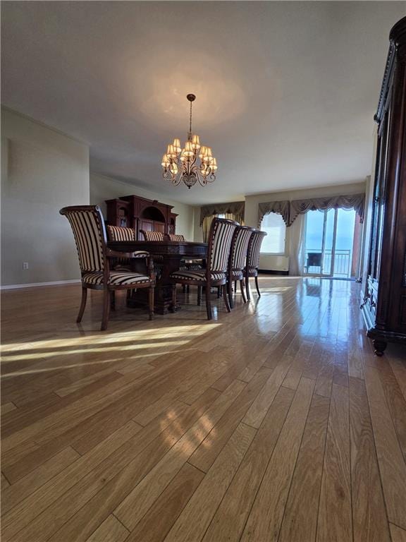 dining space featuring hardwood / wood-style floors, baseboards, and a chandelier