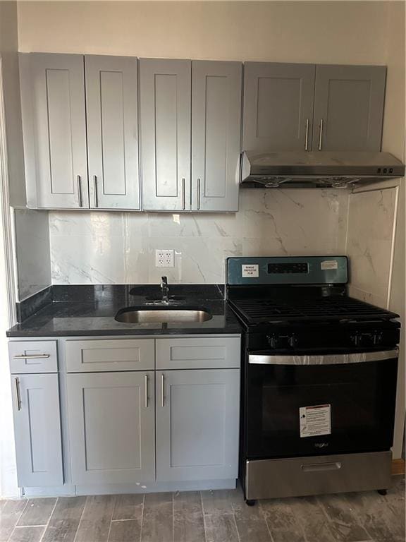 kitchen with gray cabinetry, decorative backsplash, sink, and stainless steel range