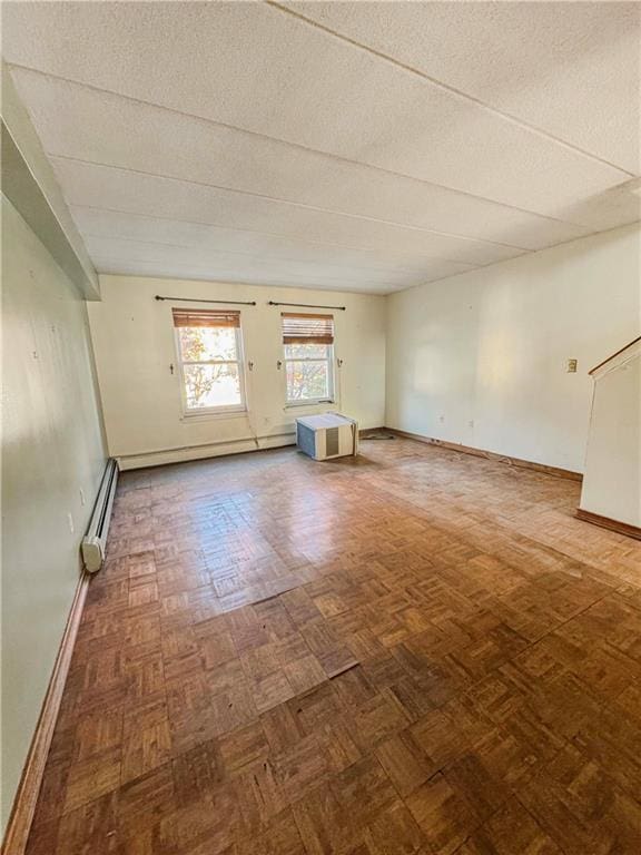 unfurnished room with parquet flooring, a textured ceiling, and a baseboard radiator