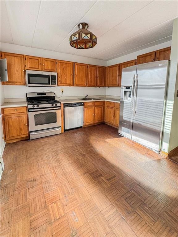 kitchen with sink, appliances with stainless steel finishes, and light parquet floors