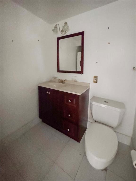 bathroom with toilet, vanity, and baseboards