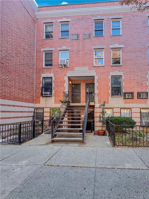 view of front of home with stairway, fence, cooling unit, and brick siding