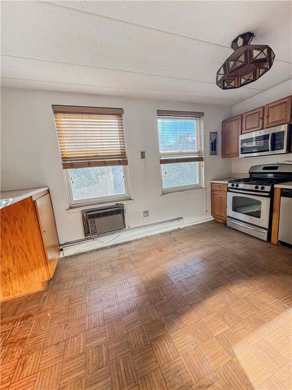 kitchen with stainless steel appliances, light countertops, brown cabinetry, and a wall mounted AC