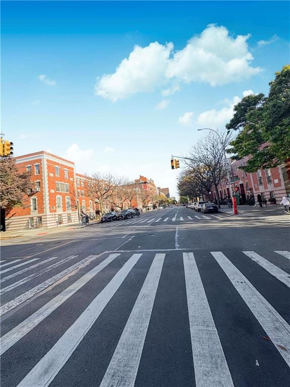 view of street with traffic lights, curbs, sidewalks, and street lights