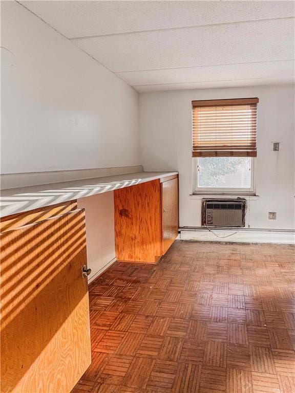 interior space with dark parquet floors and a wall unit AC