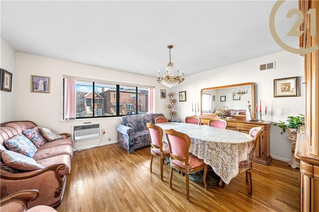 dining space with a wall mounted air conditioner, light wood-type flooring, and a chandelier