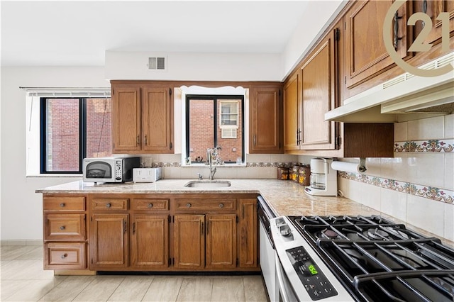 kitchen featuring decorative backsplash, white dishwasher, extractor fan, sink, and stainless steel gas stove