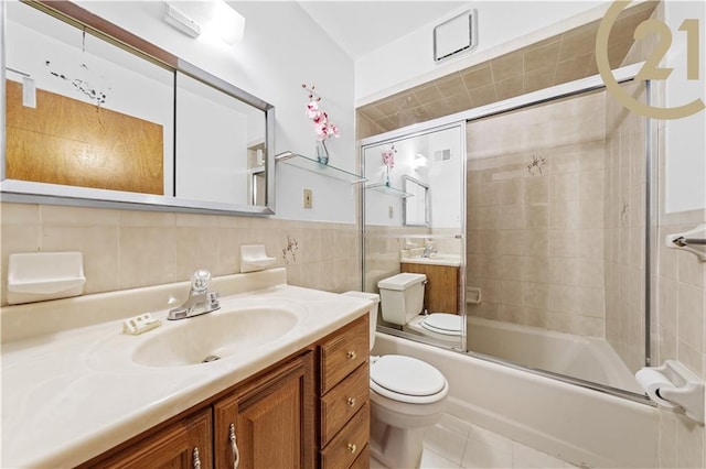 full bathroom featuring vanity, toilet, tile walls, and bath / shower combo with glass door