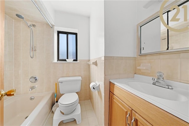 full bathroom with vanity, tiled shower / bath, tile patterned flooring, toilet, and tile walls