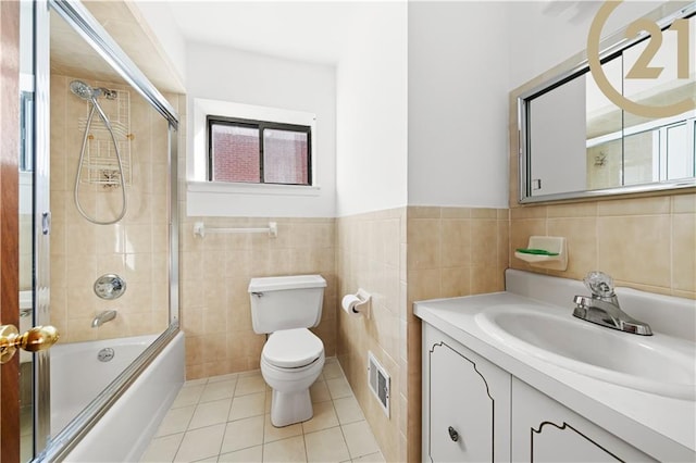 full bathroom with vanity, tile patterned floors, combined bath / shower with glass door, toilet, and tile walls