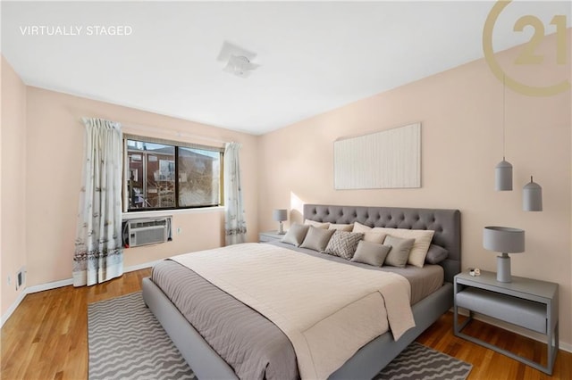 bedroom with a wall mounted air conditioner and hardwood / wood-style flooring