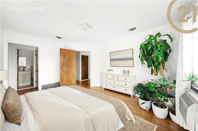 bedroom with ensuite bathroom and wood-type flooring