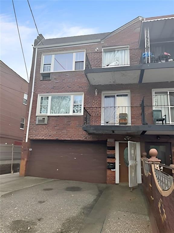 multi unit property featuring brick siding, a balcony, and an attached garage