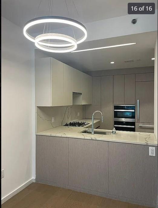 kitchen featuring sink, light stone counters, decorative backsplash, appliances with stainless steel finishes, and hardwood / wood-style flooring