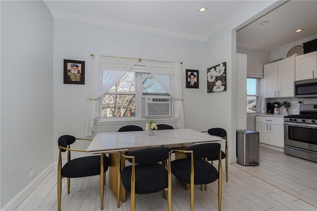 dining area featuring cooling unit, light wood-style flooring, and baseboards