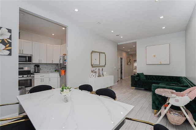 dining area with light wood finished floors and recessed lighting