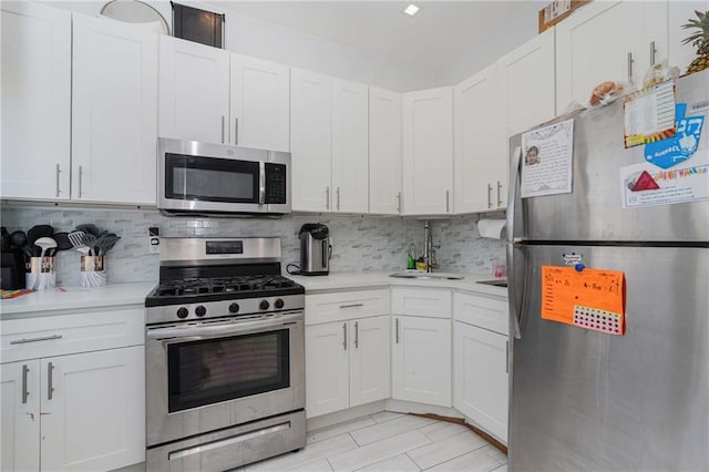 kitchen featuring appliances with stainless steel finishes, white cabinets, light countertops, and a sink