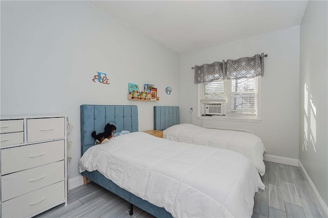 bedroom featuring light wood-style flooring, baseboards, and cooling unit