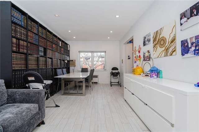 home office featuring light wood-style floors, recessed lighting, and radiator