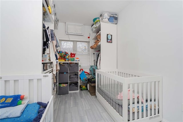 bedroom featuring a nursery area and wood finish floors