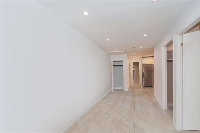 hall featuring light wood finished floors, baseboards, and recessed lighting