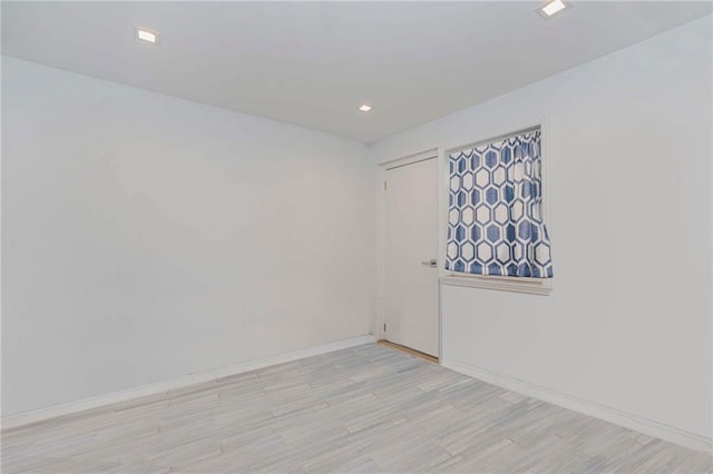 unfurnished room with light wood-type flooring and baseboards