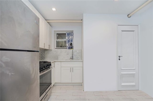 kitchen with white cabinets, a sink, stainless steel appliances, light countertops, and backsplash