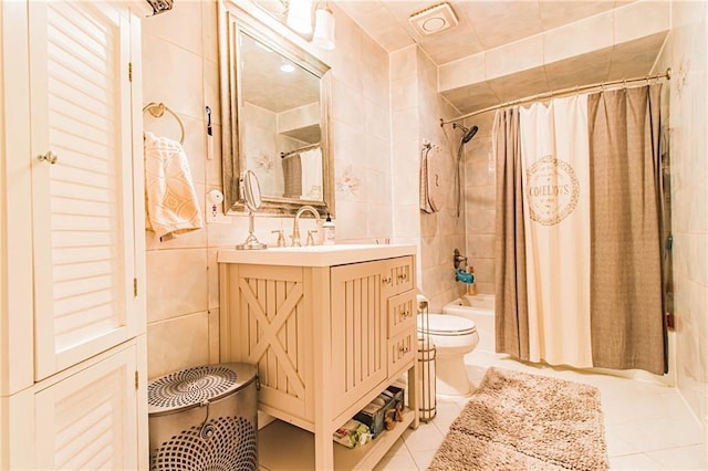 full bathroom featuring tile patterned flooring, shower / bath combination with curtain, toilet, vanity, and tile walls