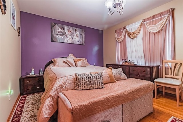 bedroom with an inviting chandelier and light hardwood / wood-style flooring