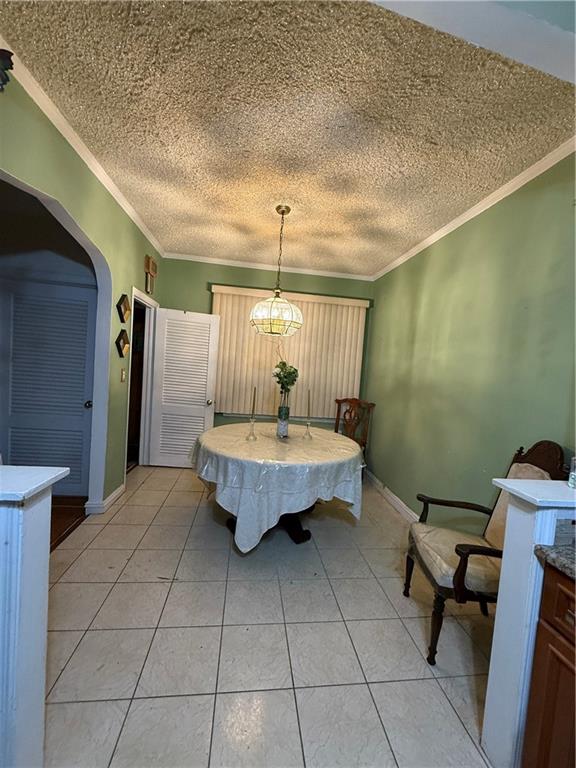 dining area with crown molding, a textured ceiling, and light tile patterned floors