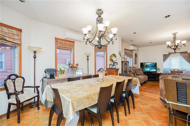 dining space with light parquet floors, an AC wall unit, and a notable chandelier