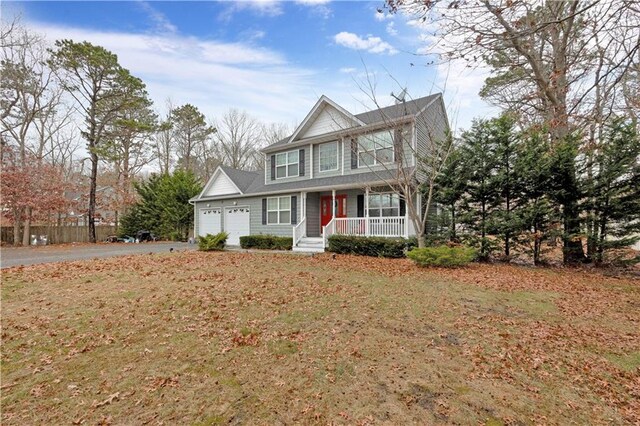 view of front of home with covered porch, a front yard, and a garage