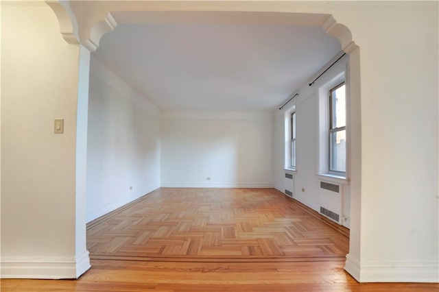 empty room with light parquet flooring and radiator