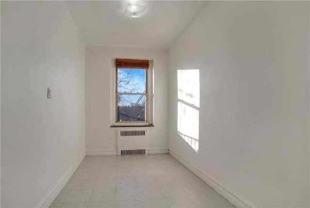 unfurnished room with light floors, radiator heating unit, and baseboards