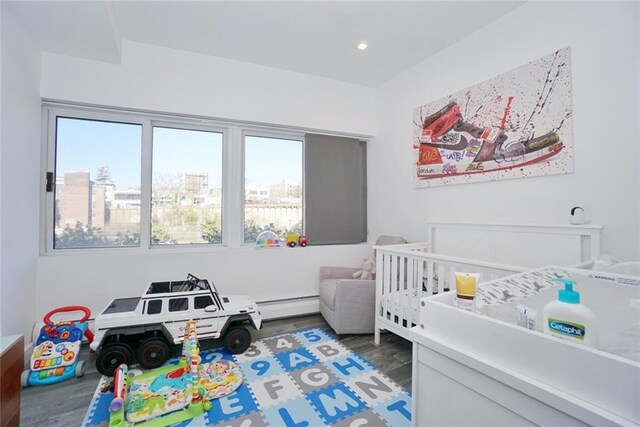 80 Bay St Unit 4A, Staten Island, NY 10301 - bedroom featuring wood finished floors, a baseboard radiator, a nursery area, a view of city, and recessed lighting
