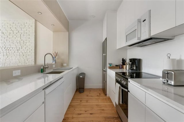 kitchen with white cabinets, light hardwood / wood-style floors, sink, and appliances with stainless steel finishes