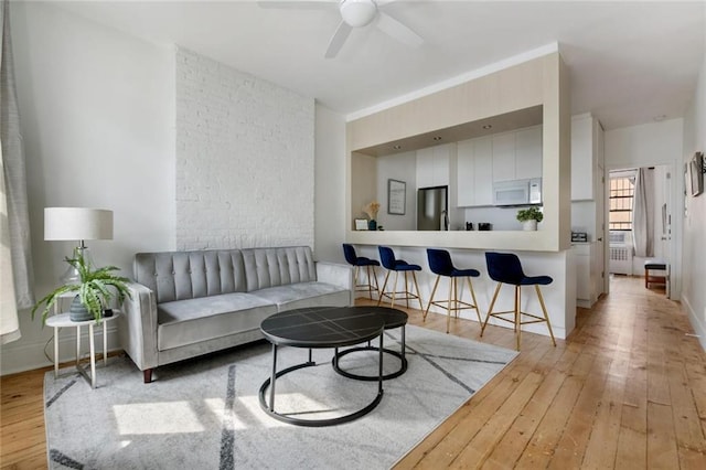 living room featuring radiator heating unit, light hardwood / wood-style floors, and ceiling fan